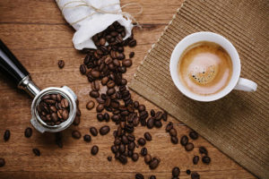 coffee beans spilling out from bag beside a latte