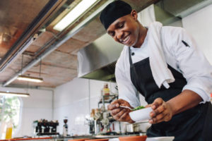 chef at work in kitchen spooning out food into bowls