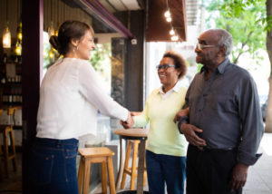 senior couple being greeted by restaurant hostess