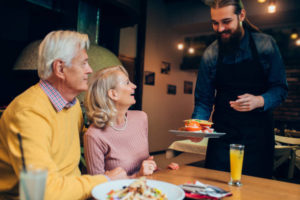 waiter bringing out orders to senior couple